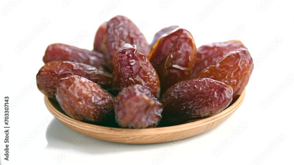 Dates fruit. Date fruits isolated on white background. Heap of Medjool dates rotating in wooden bowl close up. Tasty healthy Food Dates fruit. Date fruits isolated on white background. Heap of Medjool dates rotating in wooden bowl close up. Tasty healthy Food