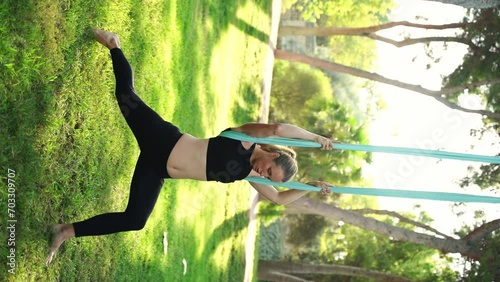 Experienced female instructor lead aerial yoga session in public park for women in hammocks, providing safe approach. Stretching lessons create prioritizing safety. Health body maintenance photo