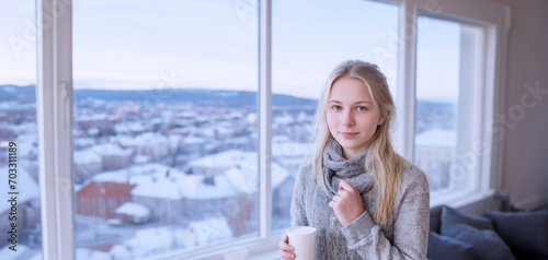 primo piano di giovane donna nordica in luminoso ambiente abitazione, ufficio con vista di panorama invernale