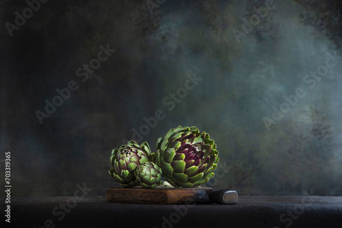 Artichokes on a wooden board. Artichoke fruits. Dark background. Copy space.