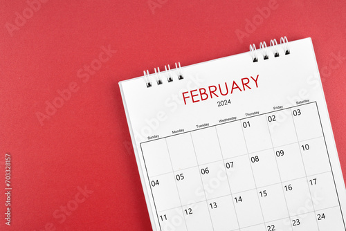 February 2024 desk calendar on red background.