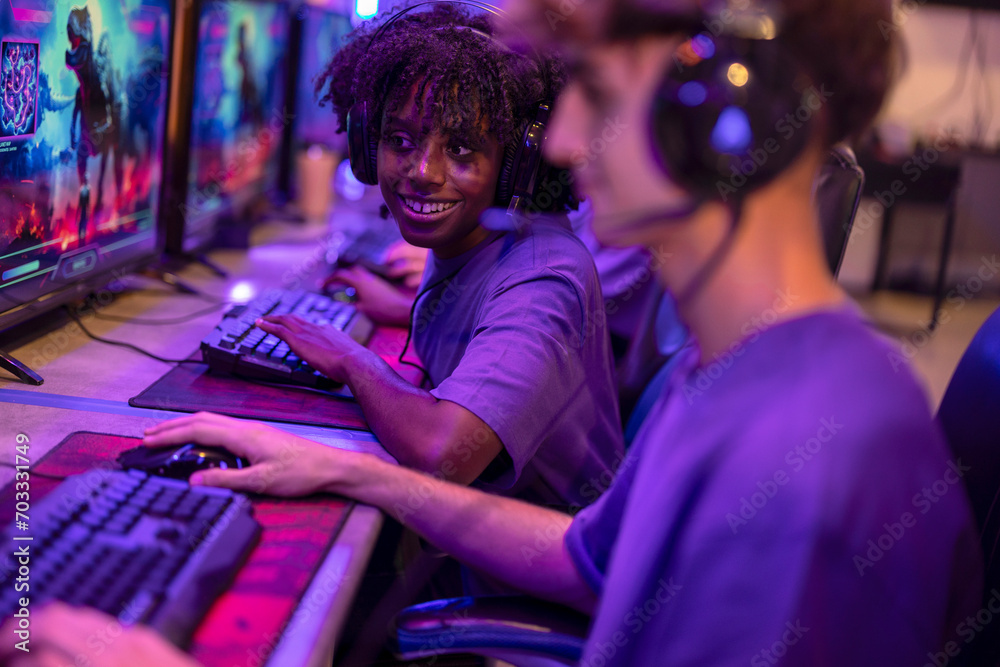 young African American woman looking attentively at her partner's computer while smiling and playing online