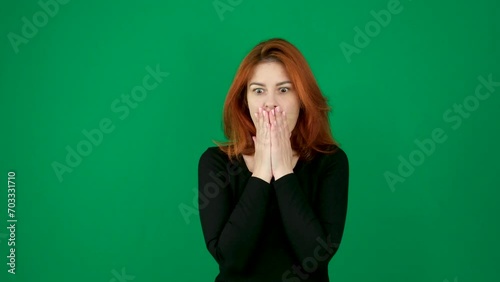 Surprise, close your hand to your mouth, dilate your pupils, shock. Is this really true against a green background, a woman with red hair and black clothes