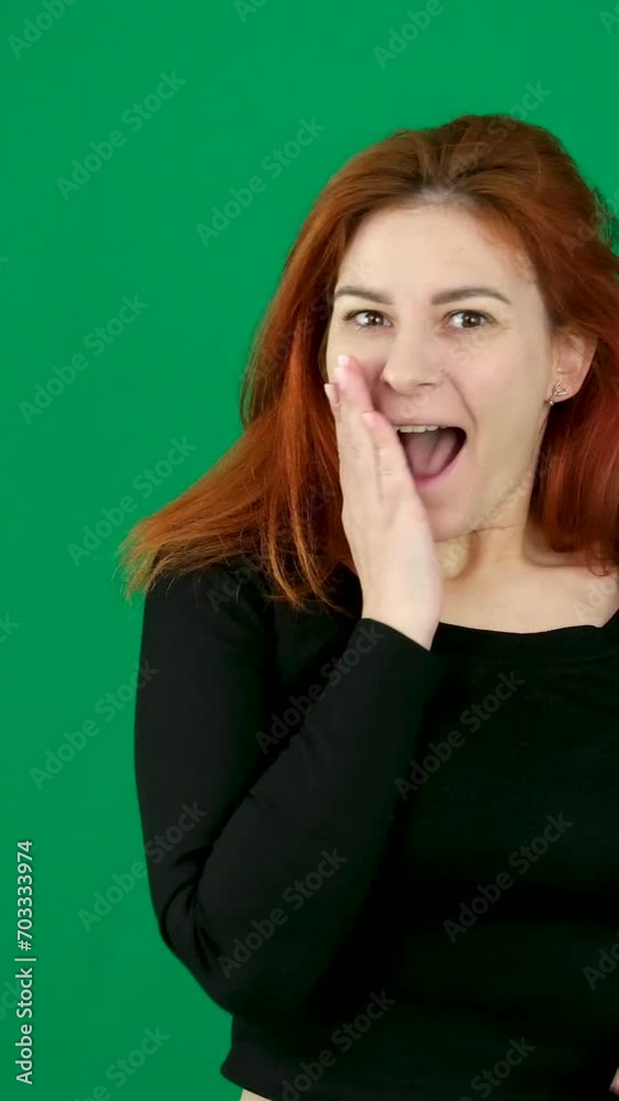 Shock surprise close your mouth with your hand jump up joyfully winning, Victory woman on a green chromakey background, red hair, black clothes.