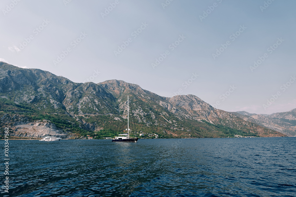 Sailboat sails on the blue sea along a mountain ridge