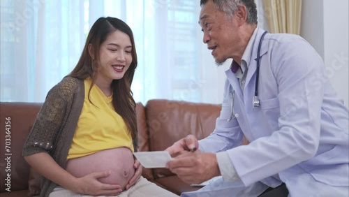 Asian pregnant woman visit gynecologist doctor at medical clinic for pregnancy consultant. Doctor examine pregnant belly for baby and mother healthcare check up. photo