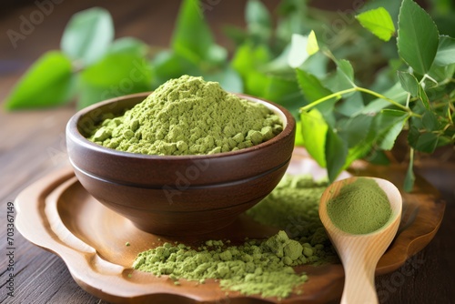 Moringa green powder for trendy superfood and drink supplement in wooden bowl with plant leaves photo