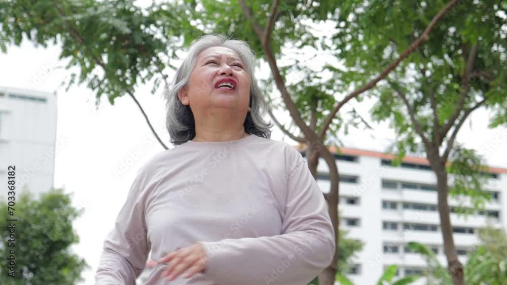 An elderly Asian woman is exercising outdoors. She is tired and hot. Heat stroke disease. Health care An elderly Asian woman is exercising outdoors. She is tired and hot. Heat stroke disease. Health care