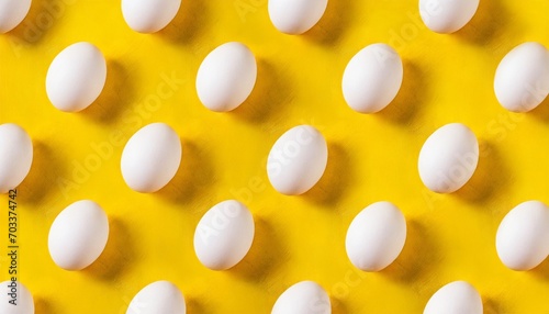 white eggs pattern on a yellow background full frame of white chicken eggs top view