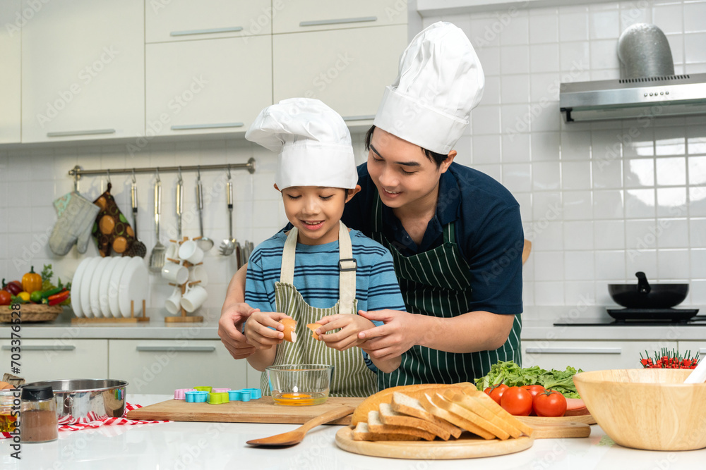 Happy moment asian father and son cooking breakfast in the kitchen. Dad and child asian family having fun preparing food bread egg sandwich. Positive parent and kid nice relationship