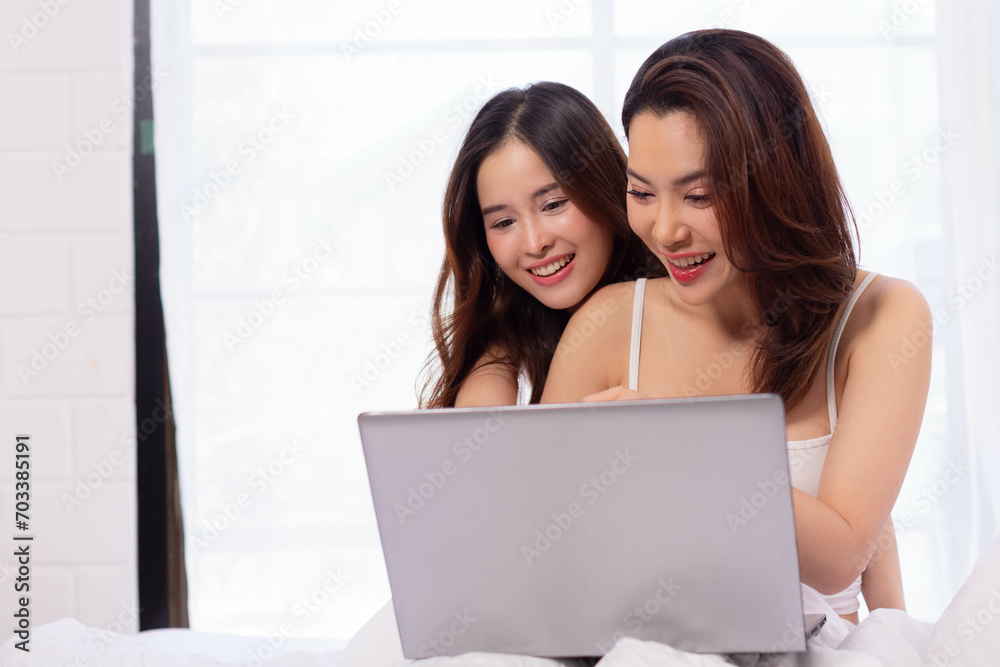 asian LGBT Lesbian couples are using laptops to search for information to buy a new home. while embracing each other in bed. asian LGBT Lesbian couples are using laptops to search for information to buy a new home. while embracing each other in bed.