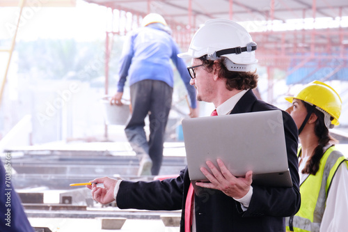 Wallpaper Mural Engineer in safety helmet holding laptop working on job site. Torontodigital.ca