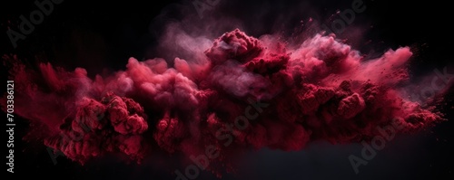 Explosion of maroon red colored powder on black background photo