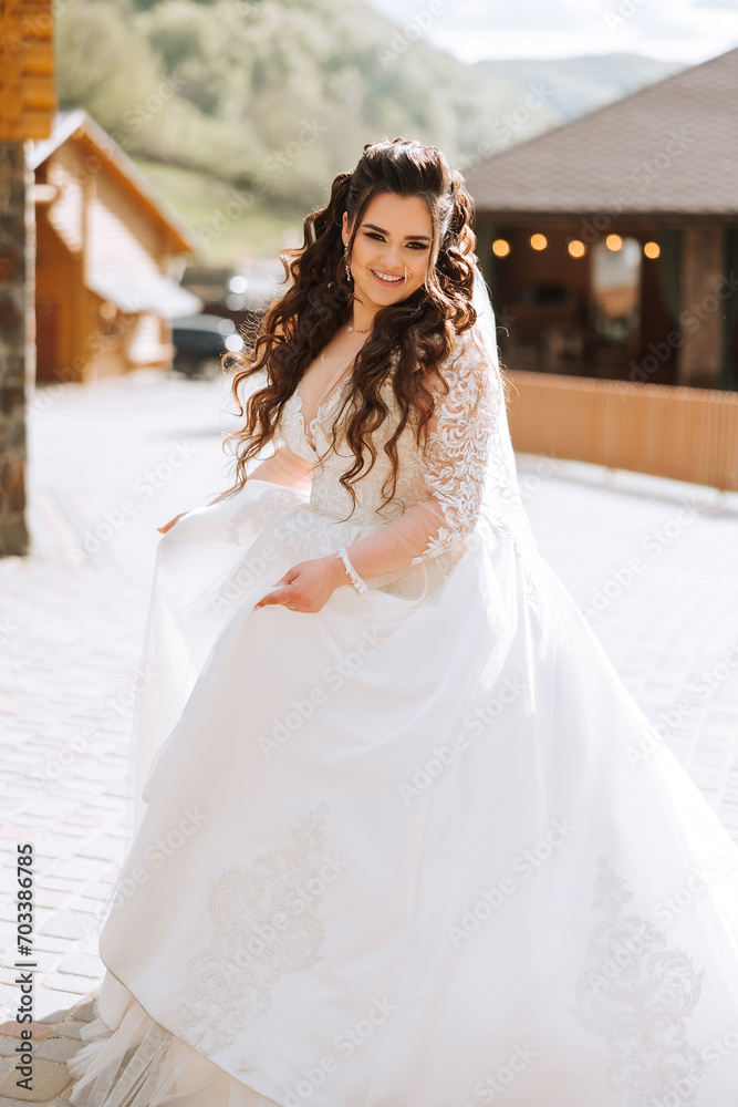 Naklejka premium Curly bride twirls in her wedding dress. Magnificent dress with long sleeves, open bust. Summer wedding