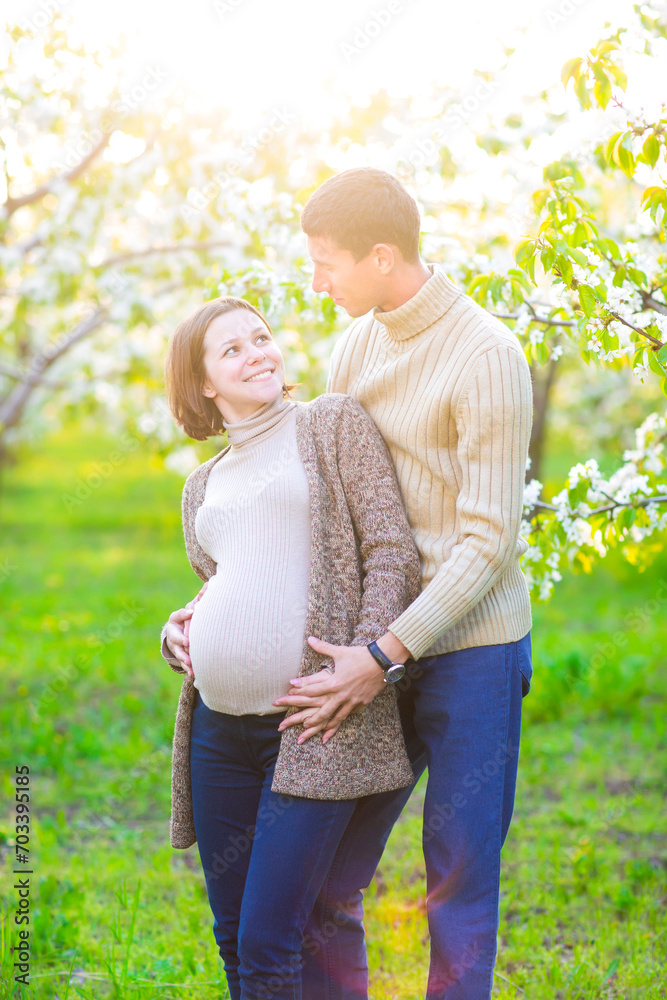 Happy pregnant couple in the blossom garden Happy pregnant couple in the blossom garden