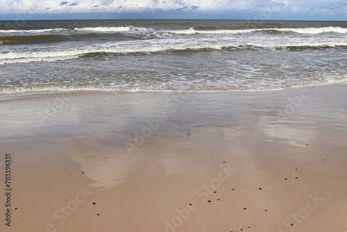 Blue sky and white clouds reflected in wet beach sand