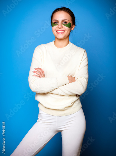 Beautiful young girl with green patches under eyes on blue background