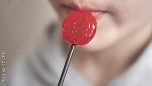 a child licks red candy, photo