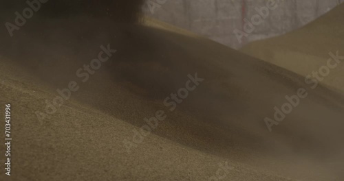 Sand shifts and slides under the wheel of digger truck close up slow motion construction site dust photo