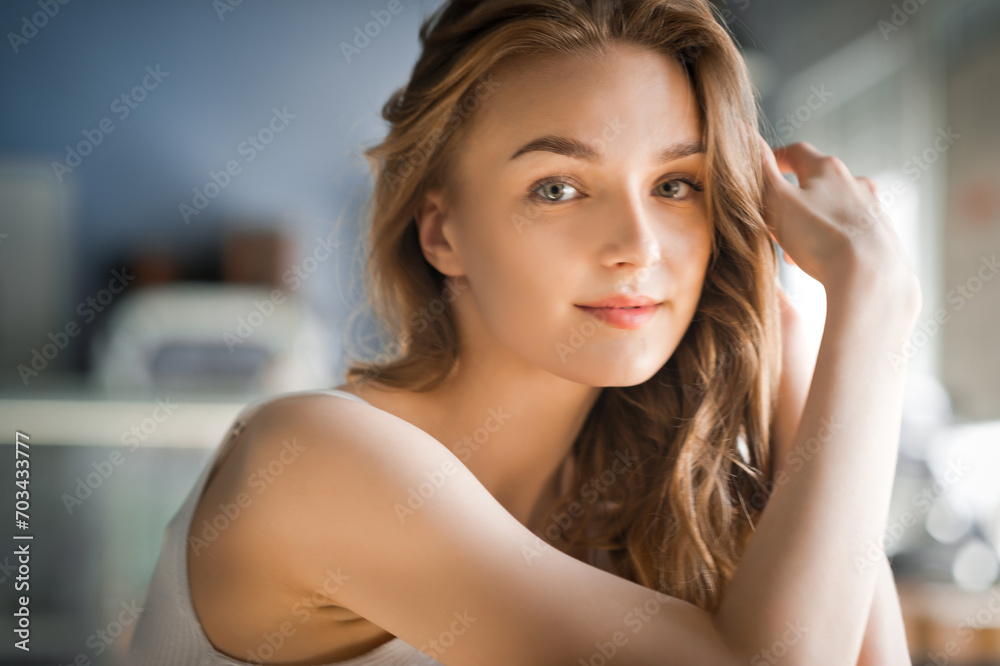 features a woman with long brown hair and her hand on her head, posing