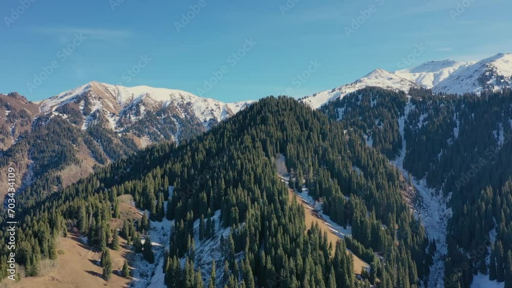 Flight over the peaks of the Tien Shan foothills with spruce slopes and snow capped peaks. Flight over the peaks of the Tien Shan foothills with spruce slopes and snow capped peaks.