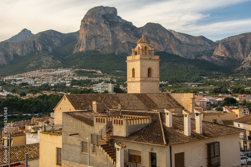 View of the town of Polop de la Marina with medieval Church of San Pedro and the high mountains at the back in Marina Baixa, Alicante, Spain