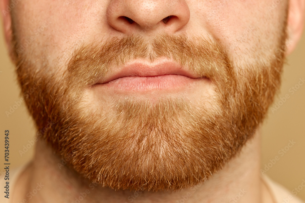 Obraz premium Cropped close up portrait of face young calm man with well kept skin and well-kept beard against beige studio background. Concept of beauty treatment, selfcare and hygiene, cosmetic, spa.