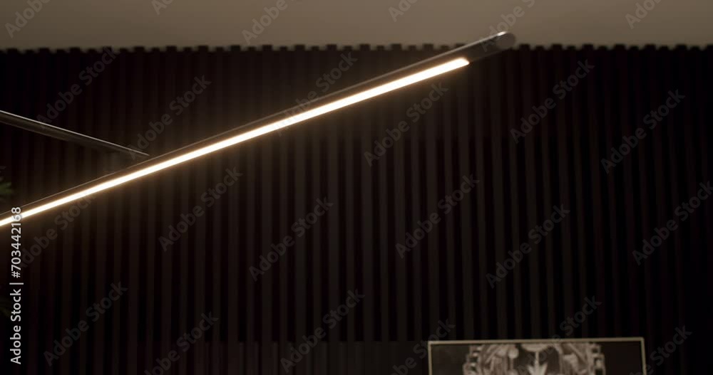 Black minimalist and modern linear floor lamp in black interior with wooden line. Minimalist Interior with lighting equipment. Contemporary modern lamp. Luxury Chandelier. Black minimalist and modern linear floor lamp in black interior with wooden line. Minimalist Interior with lighting equipment. Contemporary modern lamp. Luxury Chandelier.