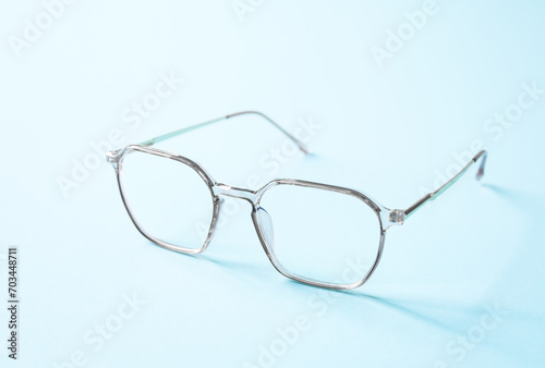 Stylish white plastic eyeglasses isolated on light blue background perspective view