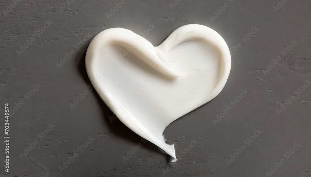 Obraz premium White beauty skincare cream swipe smear in heart shape on a dark surface