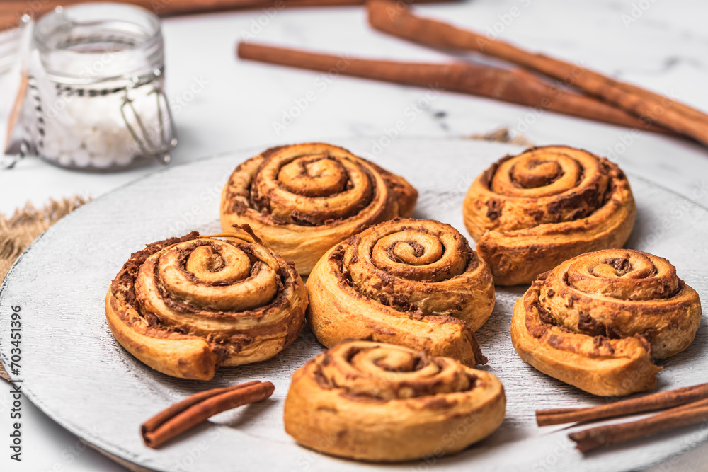 Homemade cinnamon rolls on white plate on white marble background Homemade cinnamon rolls on white plate on white marble background