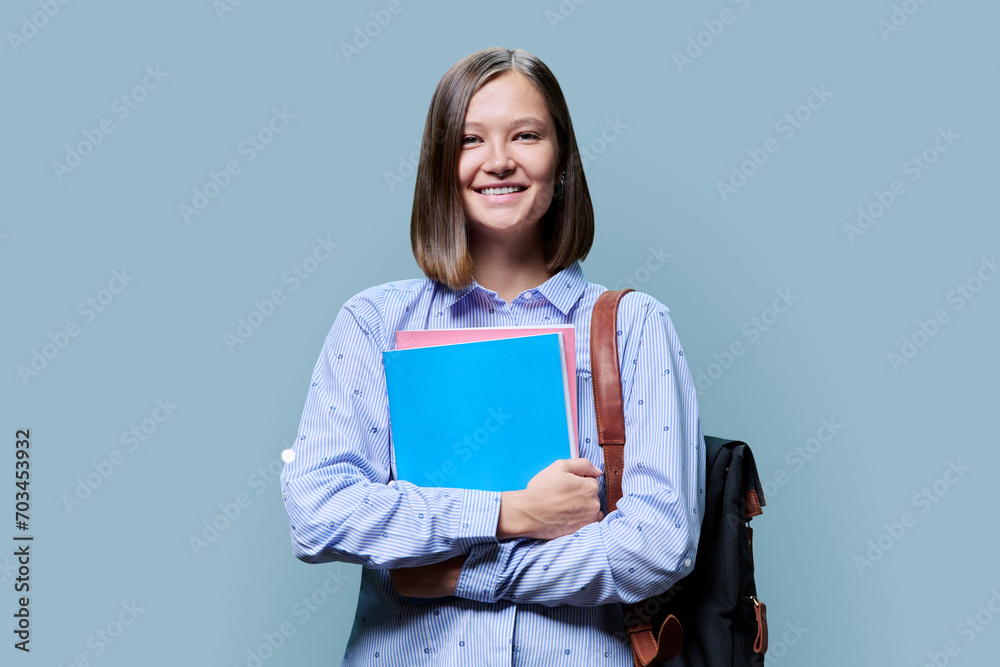 Obraz premium Portrait of smiling female college student looking at camera on blue background