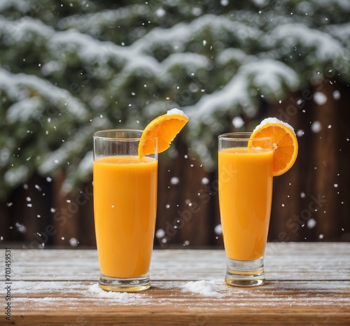 Two glasses of fresh orange juice on a wooden table in front of the snowfall