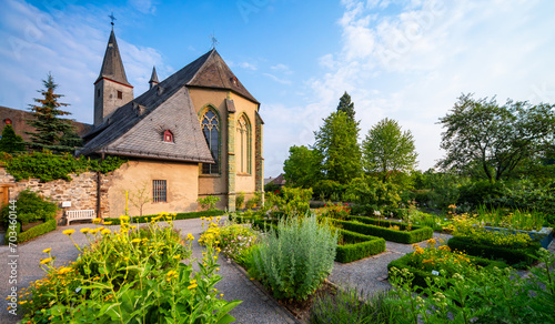 Garden panorama of the monastery garden of “Kloster Oelinghausen“ a medieval religious place with old church in Sauerland, Germany with medicinal herbs and flower beds on a sunny summer morning. 