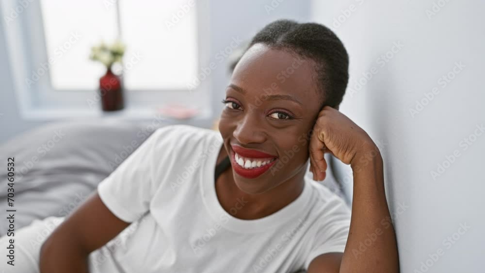 Cheerful african-american woman winks at camera, lying in bedroom with a happy, sexy expression Cheerful african-american woman winks at camera, lying in bedroom with a happy, sexy expression