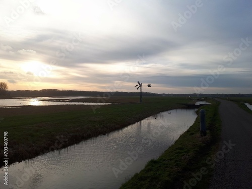 Serene rural landscape with a canal and green fields at sunset