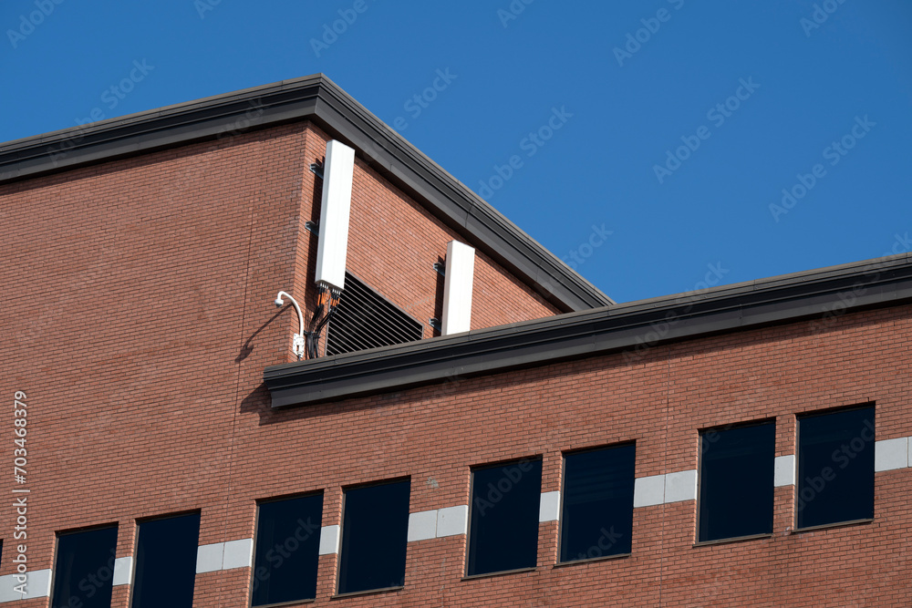 Two white antenna on a red brick wall