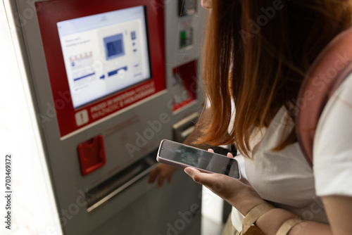 Young woman buying tickets for public transportation. A woman uses a self-service kiosk, Modern technology concept photo