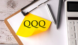 QQQ word on a yellow sticky with calculator, pen and clipboard