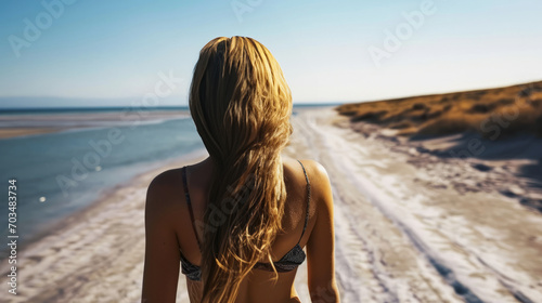 A woman in a simple swimsuit walks at the beach.