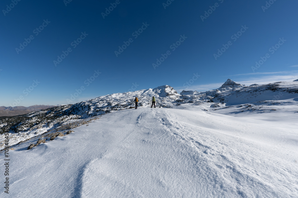 two mountaineers on their backs walking in a snowy mountain landscape. France Pyrenees two mountaineers on their backs walking in a snowy mountain landscape. France Pyrenees
