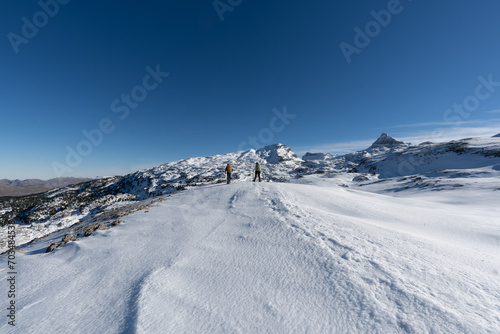 two mountaineers on their backs walking in a snowy mountain landscape. France Pyrenees