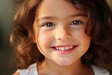 A little girl with curly hair smiles with a snow-white smile with perfectly even, clean and healthy teeth. Close-up view. Advertising of a children's dental clinic. Generative AI.