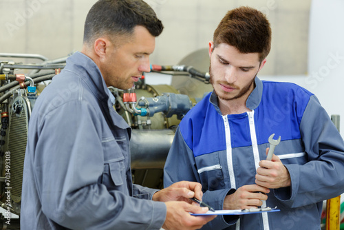 apprentice mechanic and mentor analyzing broken part
