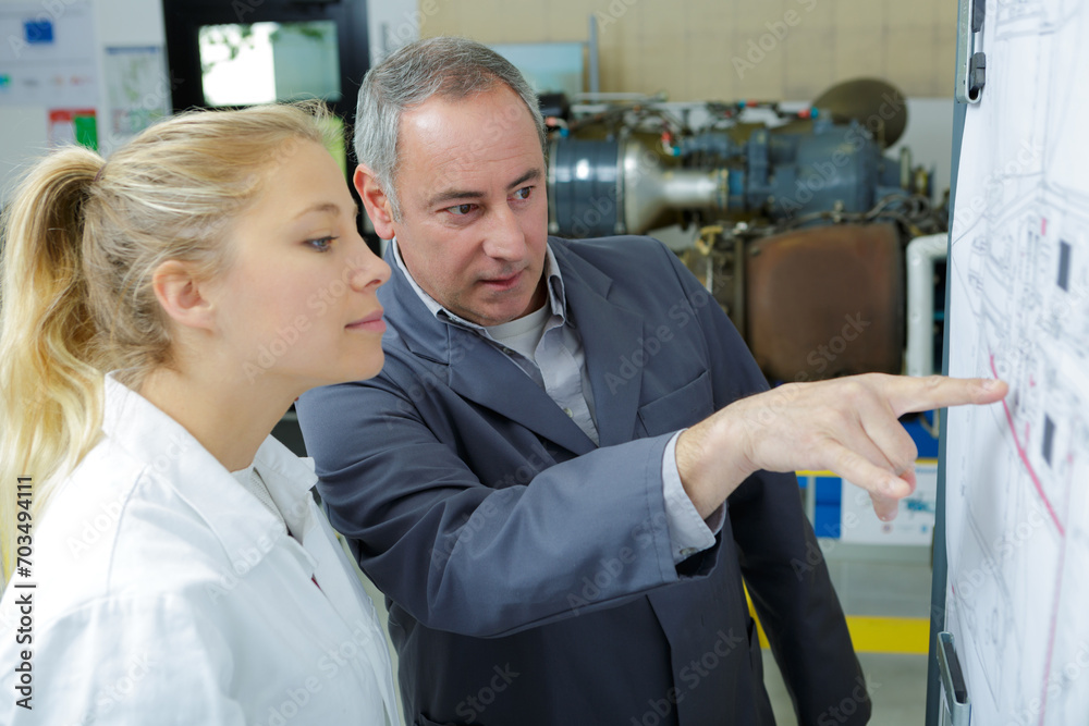 engineer showing intern a blueprint engineer showing intern a blueprint