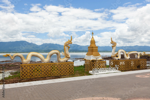 Phayao Town landmark in Northern Thailand. Naga statue and golden stupa on Phayao lake and mountains background. photo