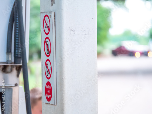 Pompe à essence et signalétique de station service avec une voiture rouge en arrière plan flou photo