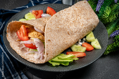 Wholegrain tortilla wraps with vegetables and chicken on a plate.