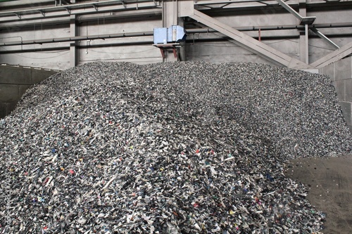 Shredded plastic pieces prepare for recycling. Raw cables material for reproduction. Sorting garbage on waste plant. Pile of scrap bottles on trash storage factory. Environmental concept photo