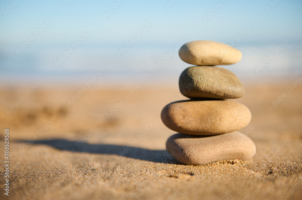 Still life with a pyramid of balanced stones stacked on the sand against sea background. Stacked pebbles. Copy ad space Still life with a pyramid of balanced stones stacked on the sand against sea background. Stacked pebbles. Copy ad space